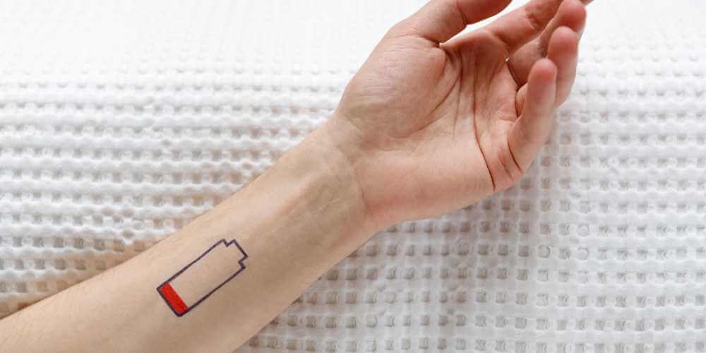 Unterarm mit leerer Batterie als Symbol für Erschöpfung und innere Energielosigkeit im Frühling