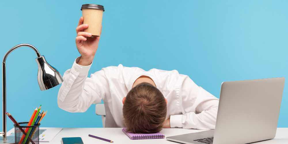 Mann wirkt überfordert im Home-Office – chaotischer Schreibtisch als Symbol für Stress und mentale Belastung